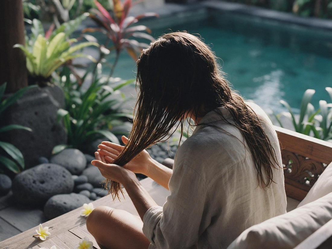 Hands working oil from a hair capsule through the damp lengths of shoulder-length hair