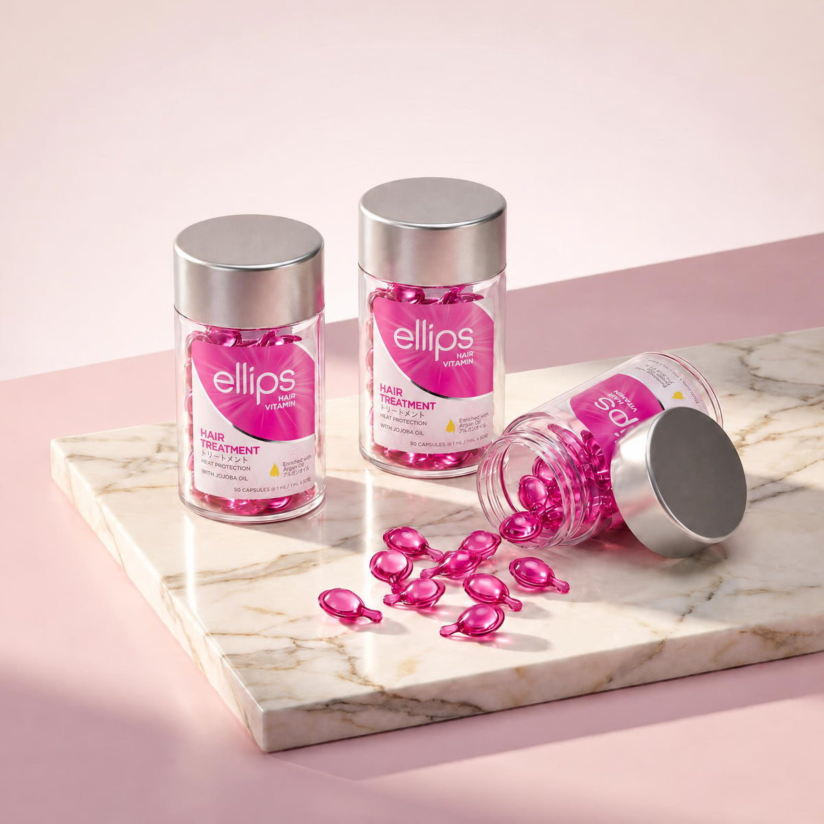 Ellips Hair Treatment jars on marble, magenta-pink capsules spilling from an open jar