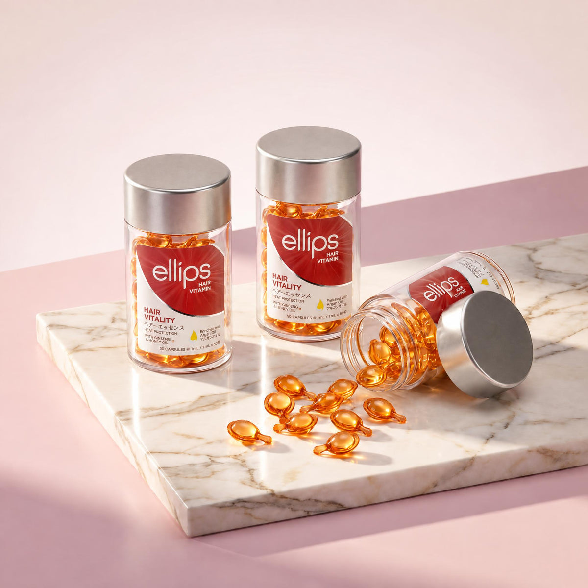 Ellips Hair Vitality jars on marble, amber capsules spilling from an open jar