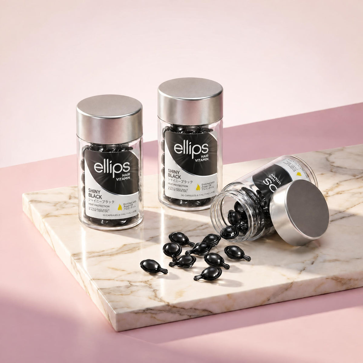 Ellips Shiny Black jars on marble, black capsules spilling from an open jar