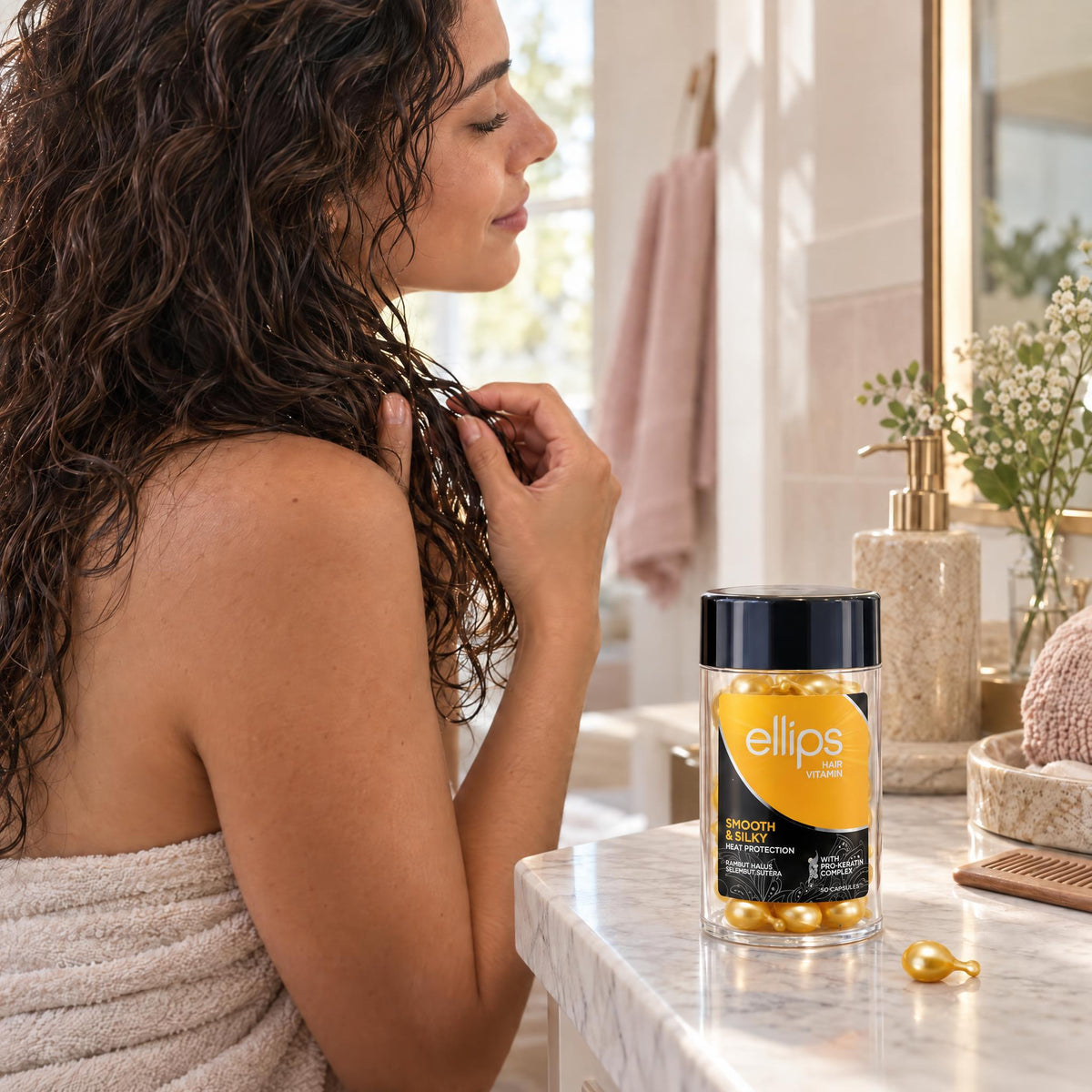 Woman working Ellips Smooth & Silky oil through damp lengths, jar on the bathroom counter